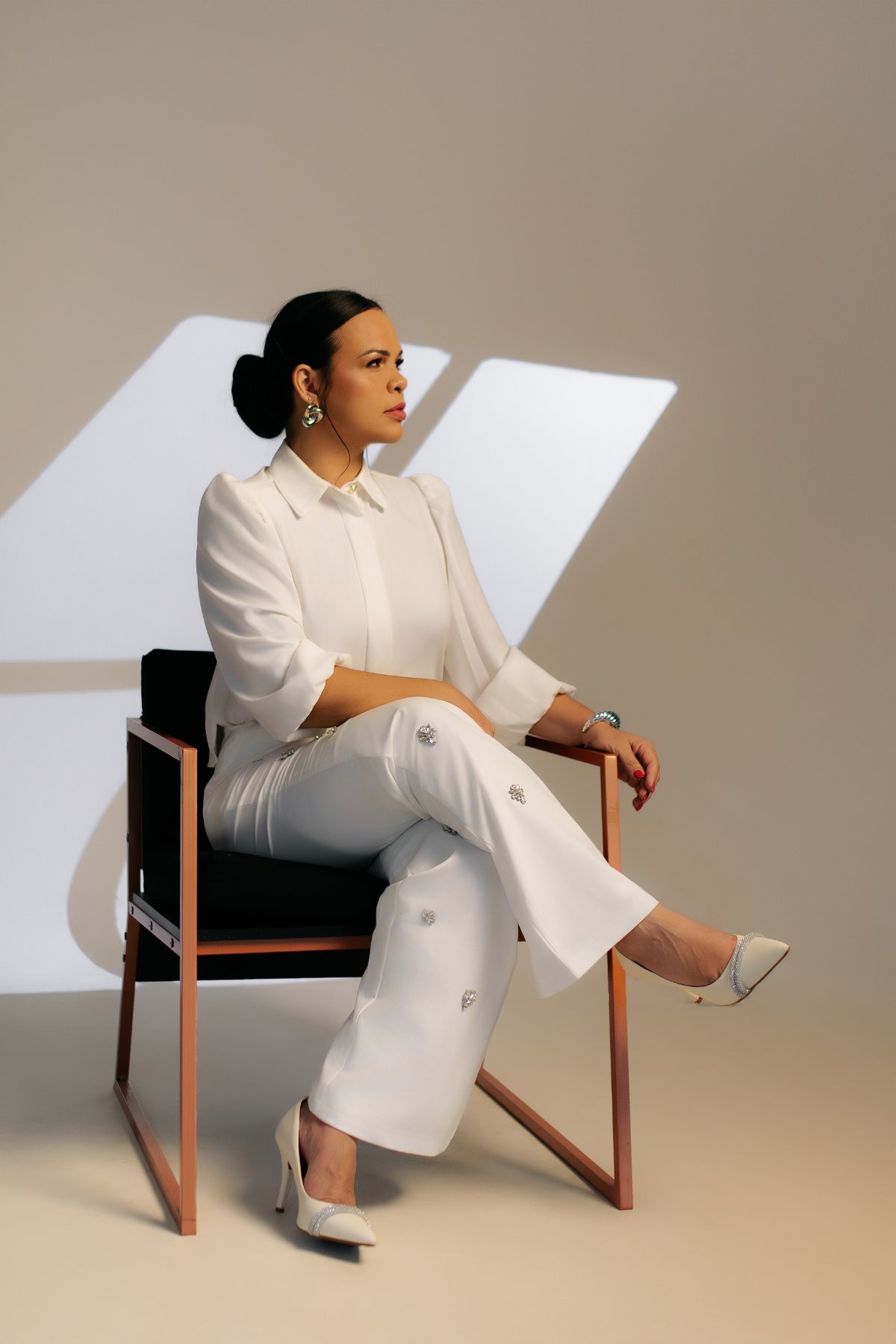 Dra. Marselle Monda sentada, em traje branco, em ensaio editorial